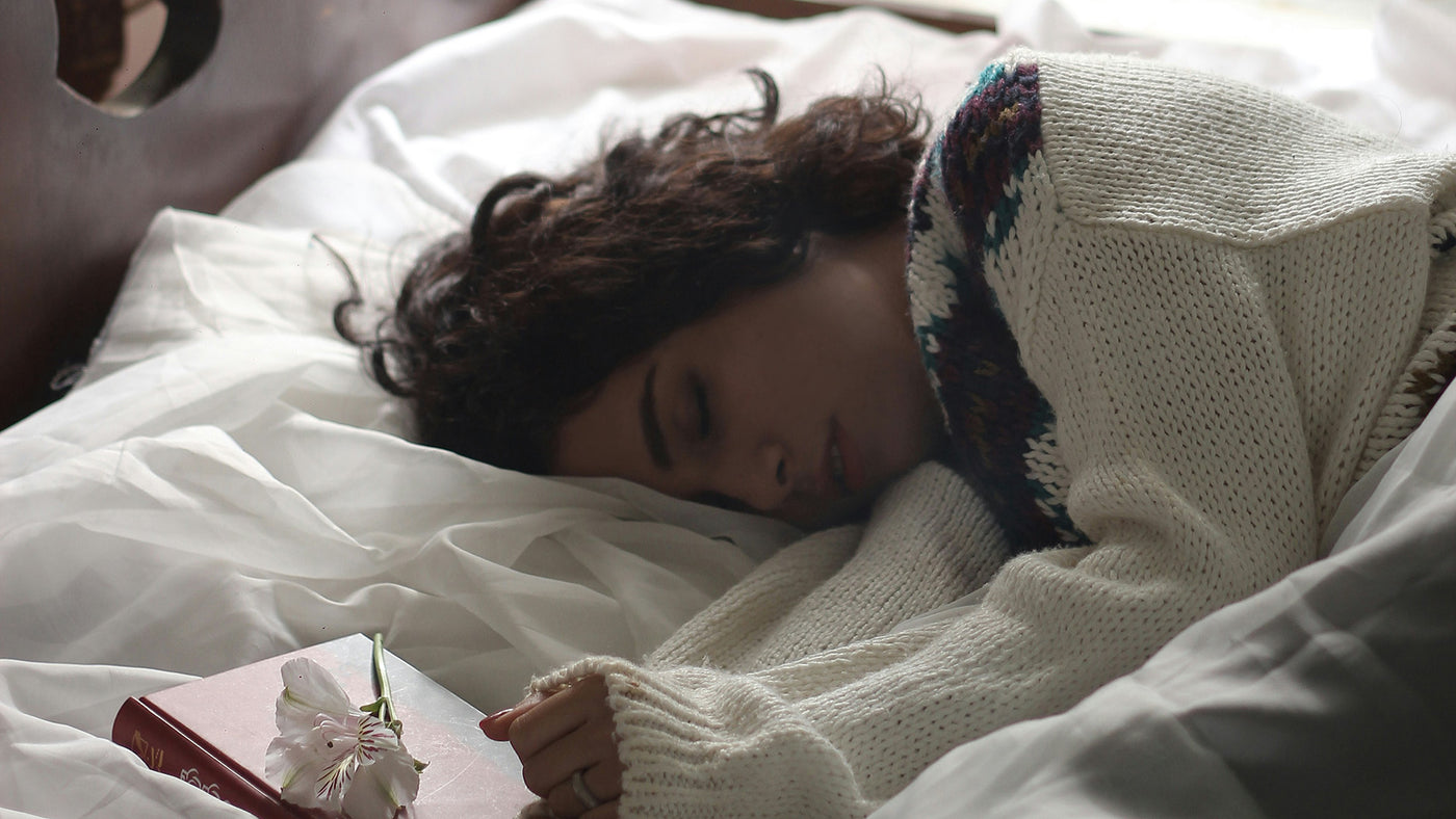 woman sleeping on bed beside book