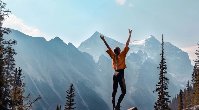 Woman on mountain throwing hands up 