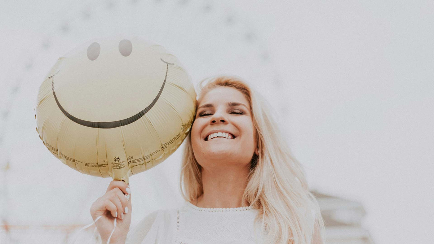 woman holding a smiley balloon