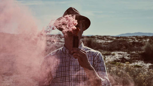 Man standing in a field, blowing vapor