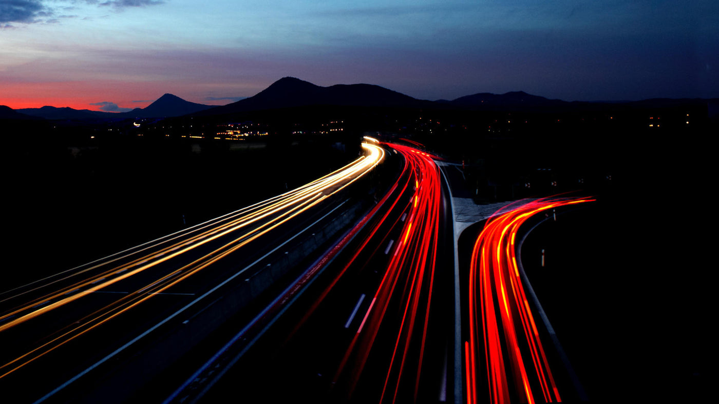 A timelapse of a busy highway at night showing fast moving vehicles.