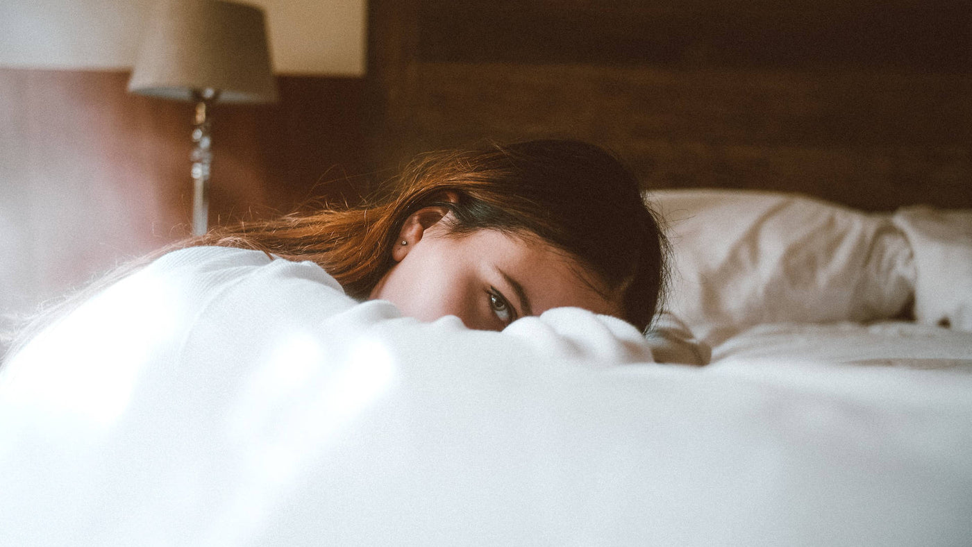 A sleepy woman resting her head on the bed.