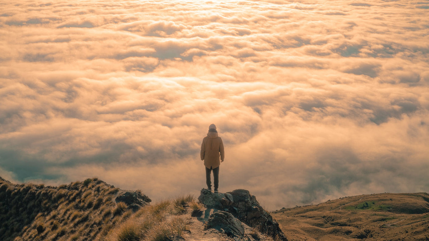 a person standing on top of a mountain above the clouds