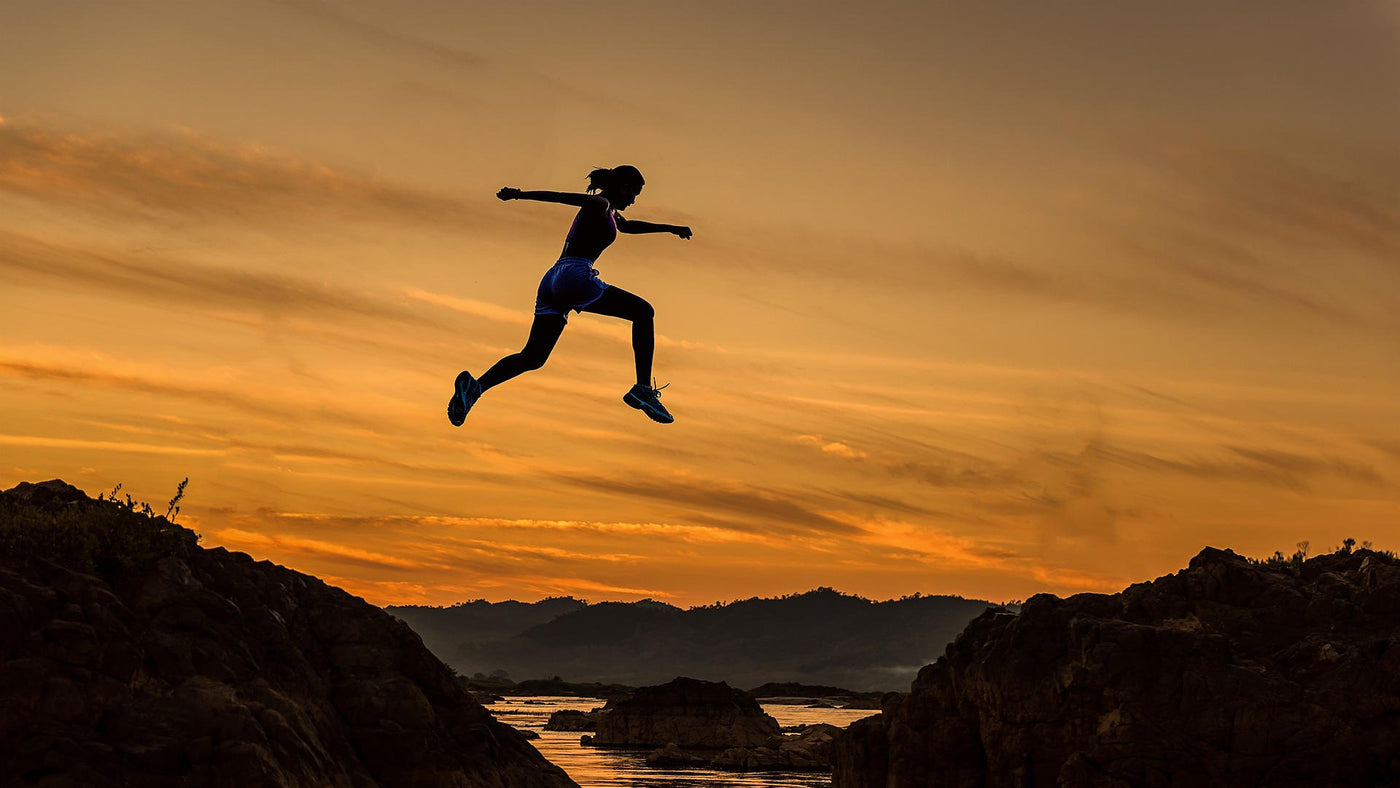 woman athlete jumping over a ravine